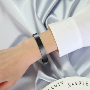 Detail of matte black stainless steel open cuff bangle on wrist with elegant background