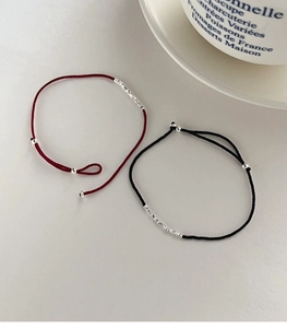 Detail von roten und schwarzen Morse-Code-Armbändern mit Silberperlen auf grauem Grund