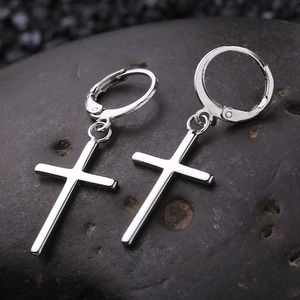 Détail macro de boucles d'oreilles créoles argentées avec pendentifs croix polis minimalistes