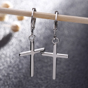 Vue macro des boucles d'oreilles croix en argent S925 suspendues sur une tige en bois