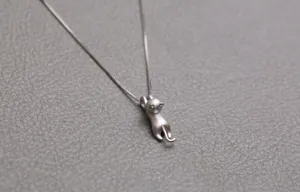 Dettaglio macro del ciondolo a forma di gatto in argento opaco su catena veneziana