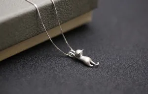 Dettaglio macro del ciondolo a gatto in argento opaco con trama fine su catena a maglia