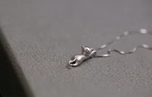 Dettaglio della collana con ciondolo a gatto in argento opaco dal design minimalista