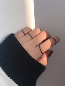 Set di cinque sottili anelli neri minimalisti indossati sulla mano con luci e ombre