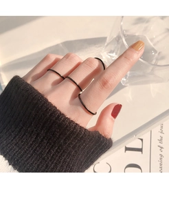 Set di anelli neri minimalisti da donna mostrati indossati su più dita con stile