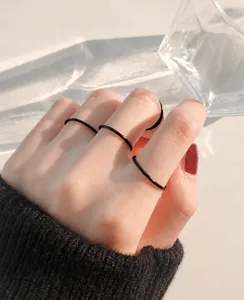 Anelli sottili neri minimalisti impilabili indossati per un look trendy coreano