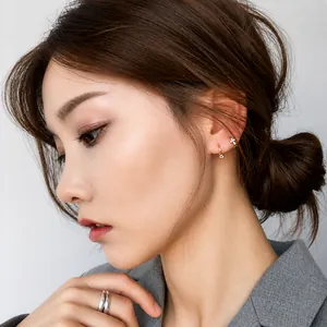 Detalle de mujer usando pendientes dorados con strass y anillo doble plateado