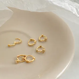 Detalle de pendientes de aro dorados con circonitas brillantes sobre un plato cerámico