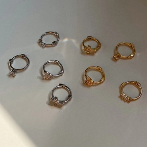 Detalle de pendientes de aro en plata y oro con colgantes de estrella y mariposa