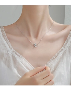 Close-up of s925 silver crescent moon necklace with blue gemstone on model's neck