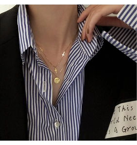 Primer plano de collares dorados en capas con cruces y moneda usados por una modelo