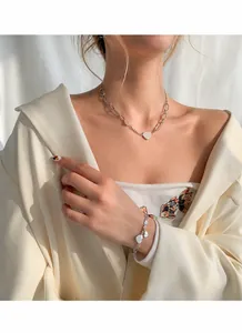 Détail d'un ensemble collier et bracelet avec pendentif cœur en argent porté par un mannequin