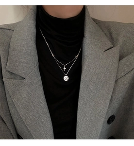 Detalle de collar de doble capa en plata con cruces y medalla redonda