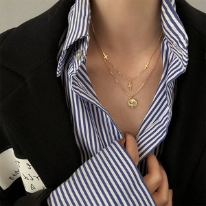 Collar de dos capas de plata 925 con colgantes de cruz dorada y moneda en una modelo