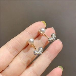 Detalle de pendientes de corazón con micro perlas y cristales en metal dorado fino