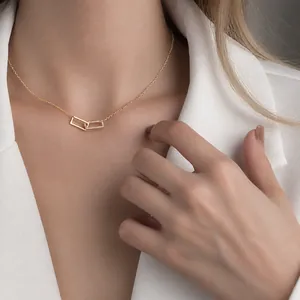Collana minimalista in oro con maglie quadrate e zirconi pavé indossata su un blazer bianco