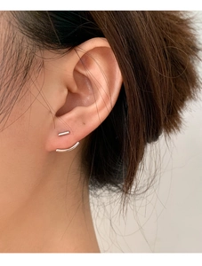 Dettaglio di orecchini minimalisti in argento con barra e design curvo sul lobo