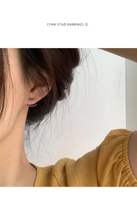 Primo piano di orecchini a perno minimalisti gun-black indossati da una modella alla moda