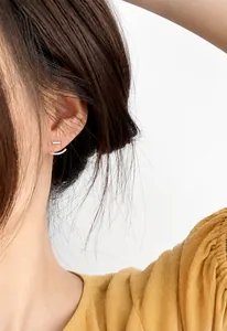 Dettaglio di orecchini geometrici in argento con barre lineari e curve sovrapposte