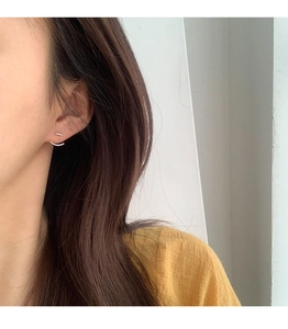 Dettaglio di orecchini a barra in argento minimalisti con design curvo su modella