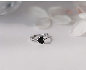 Dettaglio ravvicinato di un orecchino d'argento con design a cuore nero minimalista