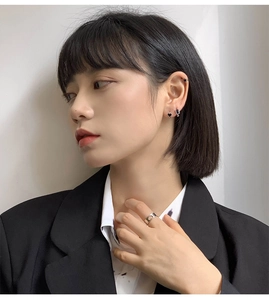 Orecchini a cuore neri e anello a cuore argento indossati con un blazer nero