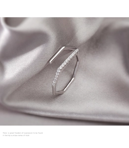 Detalle macro de un anillo geométrico de plata con circonitas en fondo de seda