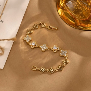 Makroaufnahme des vergoldeten Kleeblatt-Armbands mit Zirkonia-Inlay auf braunem Strukturstoff