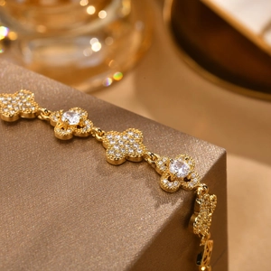 Elegantes goldenes Kleeblatt-Blütenarmband mit Zirkonia-Steinen auf Leder-Schmuckkästchen