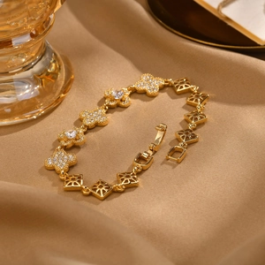 Elegantes goldenes Kleeblatt Armband mit weißen Zirkonia auf Seidenhintergrund