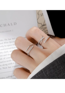 Primer plano de anillos minimalistas de plata con pavé de circonitas y diseño cruzado