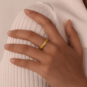 Close-up of minimalist gold-plated striped ring on finger with soft knit background