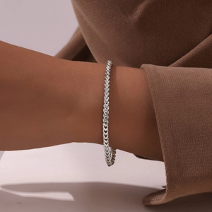 Close-up of a silver stainless steel franco chain bracelet worn on a female wrist