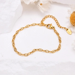 Détail d'un bracelet doré 18K avec fermoir mousqueton et étiquette K18 sur fond de pierre