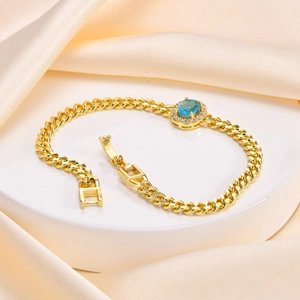Macro detail of gold Cuban chain bracelet with oval blue gemstone and micro-pavé zircons