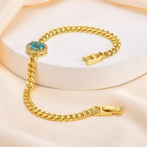 Detail of gold Cuban chain bracelet with oval blue gemstone on champagne silk