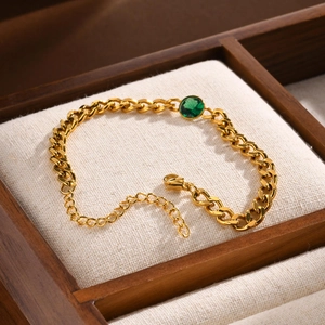 Dettaglio ravvicinato del bracciale a catena dorato con zircone verde e moschettone