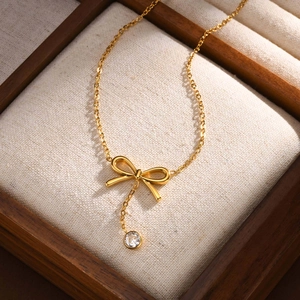 Collier élégant doré avec nœud et pendentif en zircon présenté dans son écrin à bijoux