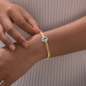 Detailed shot of golden oval bracelet with bright blue stone and zircon on a model