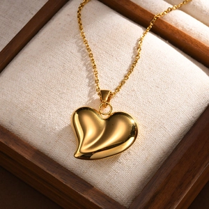 Collier avec pendentif cœur torsadé doré en 3D sur présentoir en bois et fond en lin