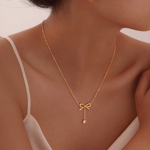 Gros plan d'un collier pendentif nœud doré avec pampille en zircon au cou