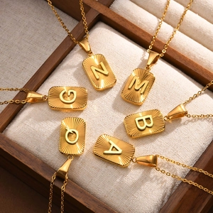 Detail of gold letter pendants with radial texture on a wooden jewelry display tray