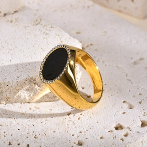 Gros plan détaillé d'une bague chevalière dorée avec gemme noire et halo de cristaux