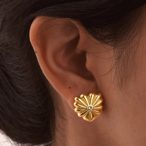 Boucles d'oreilles fleurs dorées avec diamant central portées par un mannequin