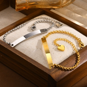 Detail of gold and silver stainless steel ID bracelets with rolo chain and heart charm