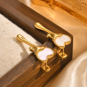 Vue macro de boucles d'oreilles cœur dorées avec incrustation en nacre blanche