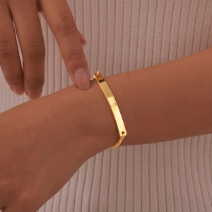 Minimalist gold bar pearl chain bracelet shown on a model wrist over a white knit sleeve