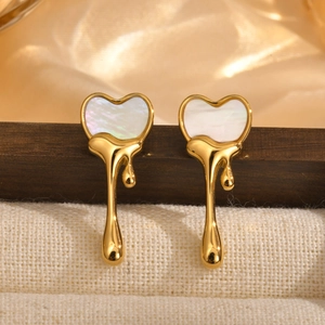 Boucles d'oreilles cœur liquide doré avec nacre blanche sur fond de tissu élégant