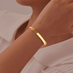 Close-up of a polished gold curved bar bracelet on wrist with elegant pearl chain detail