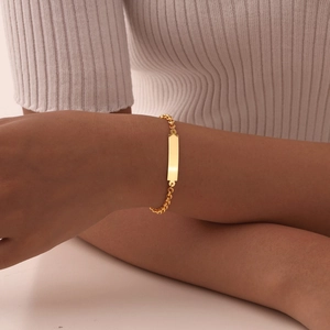 Detailopname van een gepolijste gouden roestvrijstalen ID-armband om een damespols